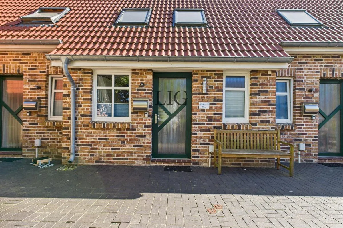 Hausfront mit Eingang am Otzumer Weg — ruhige Seitenstraße hinter den Dünen
